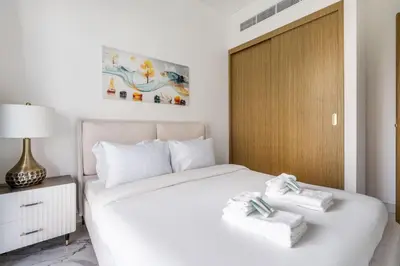 a bedroom with a white bed with towels on it at New Charming 2BR with Gym & Pool in Azizi Riviera in Dubai