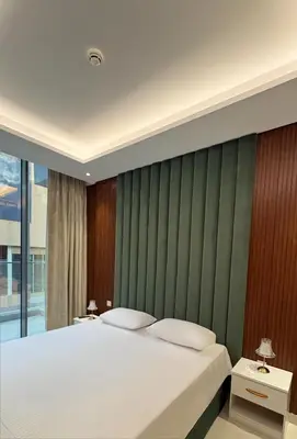 a bedroom with a large bed with a green accent wall at Spacious 1BR JVC Circle Mall at Your Doorstep in Dubai