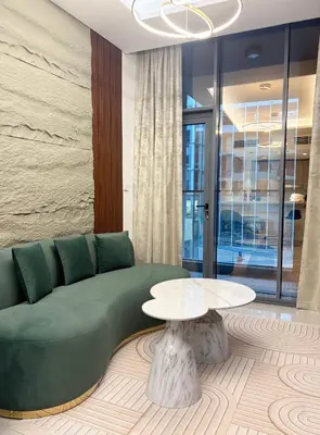 a living room with a green couch and a table at Spacious 1BR JVC Circle Mall at Your Doorstep in Dubai