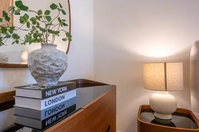 a vase sitting on a stack of books next to a lamp at Palace Residence Beach Villa - Direct Beach Access in Dubai