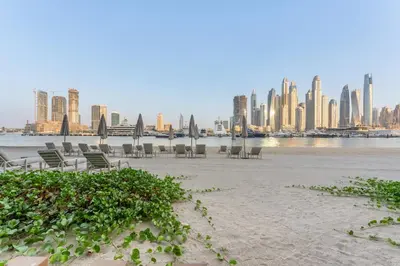 a beach with chairs and a city in the background at Palace Residence Beach Villa - Direct Beach Access in Dubai
