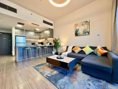 a living room with a blue couch and a kitchen at The Greendoor - Lake and Sea View, JLT in Dubai