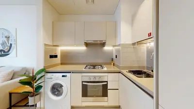 a kitchen with white cabinets and a washer and dryer at Locations l Elegant One Bedroom l City Views and Free Pool, Gym Access in Dubai