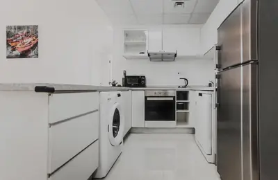 a kitchen with white cabinets and a stainless steel refrigerator at Sansa Beach Home in Dubai