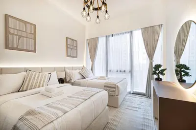 a white bedroom with two beds and a couch at Luxury Grande Suites by Hostiva - Full City View in Dubai