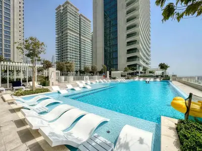 a swimming pool with white lounge chairs and buildings at TRPS - Beach Vista, Dubai Harbour - Ain Dubai View, Furnished, Private Beach Access in Dubai