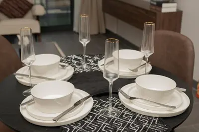 a black table with white plates and wine glasses at Crest Serene Stay for 4 Guests 1BR and Cozy Room in Dubai