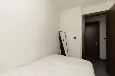 a white bed in a room with a door at Crest Serene Stay for 4 Guests 1BR and Cozy Room in Dubai