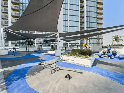 a chair in a courtyard with a building at Fancy 1BR apartment The Crest at Sobha Hartland in Dubai