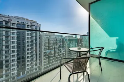 a table and chair on a balcony with a view at Studio Just Minutes Drive from Miracle Garden, Near Local Parks and Circle Mall, Binghatti Azure, JVC by Deluxe Holiday Homes in Dubai