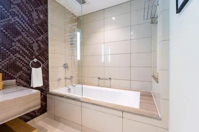 a bathroom with a tub and a glass shower at TRPS - Paramount Tower D, Business Bay - Premium 1BR Furnished, High Floor, Ready Move In in Dubai
