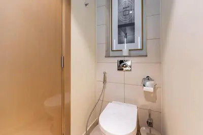 a bathroom with a toilet and a picture on the wall at TRPS - Paramount Tower D, Business Bay - Premium 1BR Furnished, High Floor, Ready Move In in Dubai