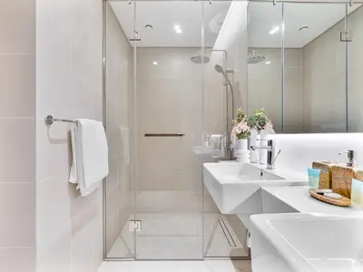 a white bathroom with two sinks and a shower at Savis Homes - Canal Front Residence Near Al Wasl Safa Park with Skyline View in Dubai