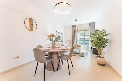 a dining room with a round table and chairs at Easy Metro and Tram Access 1BR, Offering Partial Canal, SZR, and City Views, Just Minutes from Marina Mall, Marina Diamond 6, Dubai Marina by Deluxe Holiday Homes in Dubai