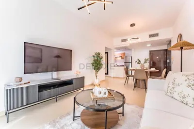 a living room with a large television and a white couch at Easy Metro and Tram Access 1BR, Offering Partial Canal, SZR, and City Views, Just Minutes from Marina Mall, Marina Diamond 6, Dubai Marina by Deluxe Holiday Homes in Dubai