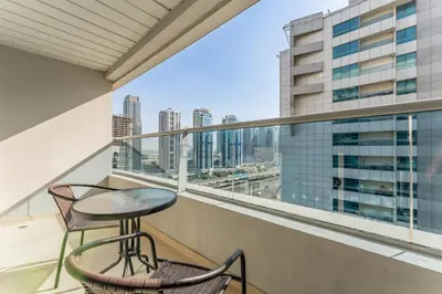 a balcony with a table and chairs and a view of the city at Easy Metro and Tram Access 1BR, Offering Partial Canal, SZR, and City Views, Just Minutes from Marina Mall, Marina Diamond 6, Dubai Marina by Deluxe Holiday Homes in Dubai