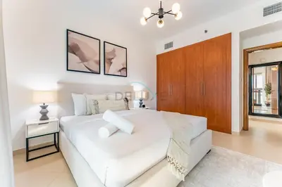 a white bedroom with a white bed and a wooden cabinet at Easy Metro and Tram Access 1BR, Offering Partial Canal, SZR, and City Views, Just Minutes from Marina Mall, Marina Diamond 6, Dubai Marina by Deluxe Holiday Homes in Dubai
