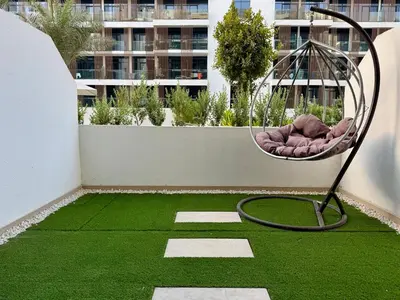 a room with a green lawn with a swing at Cozy Studio 15 Min From Burj Khalifa in Dubai