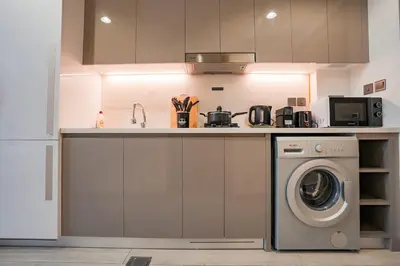 a kitchen with a washing machine and a microwave at Bright Studio in Azizi Riviera with Patio & Pool in Dubai
