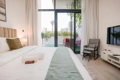 a bedroom with a large white bed and a chair at Bright Studio in Azizi Riviera with Patio & Pool in Dubai