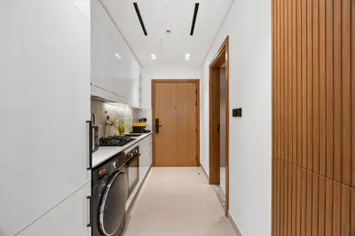 a kitchen with a washer and dryer next to a door at luxury Madrid Studio-Binghatti Azure in Dubai