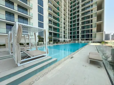 a swimming pool with lounge chairs and a building at luxury Madrid Studio-Binghatti Azure in Dubai