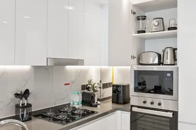 a white kitchen with a stove and a microwave at 2 bedroom apartment with private pool in Dubai