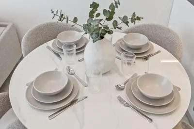 a white table with plates and silverware on it at 2 bedroom apartment with private pool in Dubai