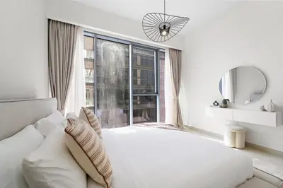 a white bedroom with a bed and a large window at Partial Canal View 2BR plus Maid close to Safa Park in Dubai