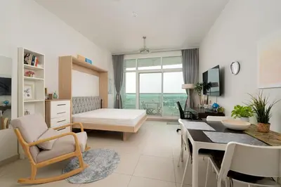 a living room with a table and a dining room at Fully Furnished Studio Hilliana Tower Sea View and Burj View in Dubai