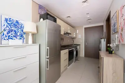 a kitchen with a refrigerator and a stove at Fully Furnished Studio Hilliana Tower Sea View and Burj View in Dubai