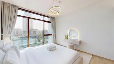 a white bedroom with a white couch and a large window at Palace Residences - Two Bedroom with Creek View in Dubai