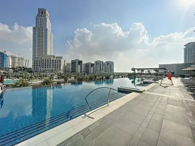 a large swimming pool with a city skyline in the background at Palace Residences - Two Bedroom with Creek View in Dubai