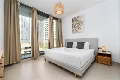 a bedroom with a white bed and a large window at Waterfront Living Bright 1 Bedroom Marina in Dubai