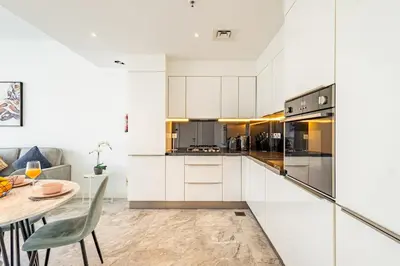 a kitchen with white cabinets and a table and a dining room at Deluxe 1BR Business Bay - with Canal and Skyline Views in Dubai