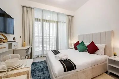 a bedroom with a large white bed with red and green pillows at Ramora Homes Azizi Riviera 40 by Vacay Xeal in Dubai
