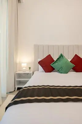 a bedroom with a white bed with red and green pillows at Ramora Homes Azizi Riviera 40 by Vacay Xeal in Dubai