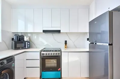 a white kitchen with a stove and a microwave at Modern 1BR Urban Escape at Blue Paradise in Dubai