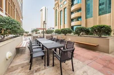 a table and chairs on a balcony with buildings at Sky-Level 2BR with Partial Marina View, Just Steps to Dubai Tram and Minutes from the Beach, Elite Residence, Dubai Marina by Deluxe Holiday Homes in Dubai