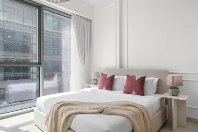 a bedroom with a white bed with red pillows and a window at 2BR with M CF7B Partial Canal View in Dubai