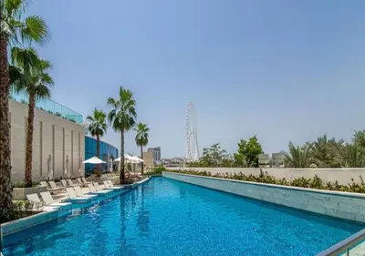 a swimming pool with lounge chairs and palm trees at Exclusive 2BD in JBR Address with Ain Dubai View in Dubai