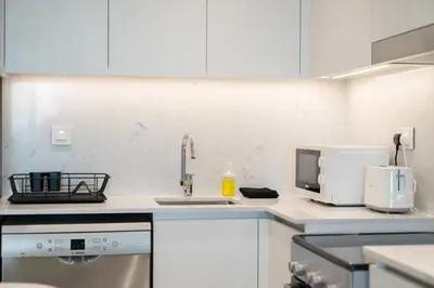 a white kitchen with a sink and a microwave at Chic 1BR Apartment near Madinat Jumeirah BurjAlArab in Dubai