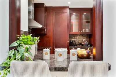 a kitchen with wooden cabinets and a counter with a bowl of fruit at 2BHK Downtown Breathtaking Burj Khalifa View in Dubai