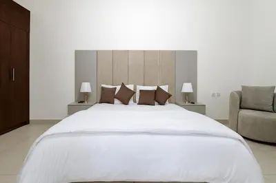 a bedroom with a large white bed and a chair at The Rosewood HH at Sarai Residence, Palm Jumeirah, 5 mins from the Iconic Atlantis The Royale in Dubai