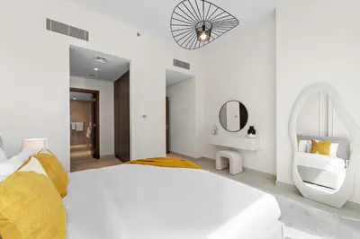 a white bedroom with a large bed and a mirror at 2BR with M CF7B Pet Friendly Stay in Dubai