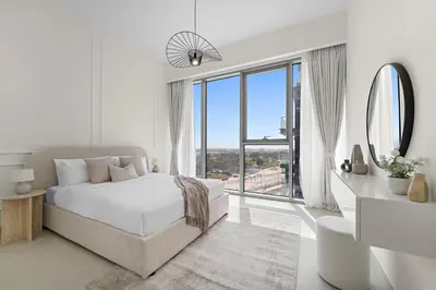a white bedroom with a bed and a large window at 2BR with M CF7B Pet Friendly Stay in Dubai