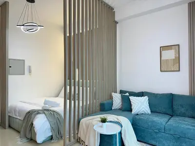 a living room with a blue couch and a bed at Minimalist Studio with Amazings Marina Canal Views in Dubai