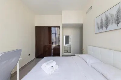 a white bedroom with a large white bed with towels on it at Modern 2BR Apartment in Merano Tower, Business Bay in Dubai