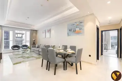a dining room and living room with a table and chairs at Vogue Downtown Mon Reve near Burj Khalifa and Dubai Mall, Two Bedroom plus kids room Apartment with Balcony and Access to all Amenities in Dubai
