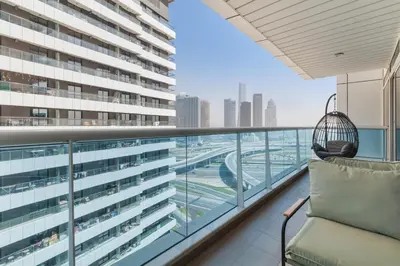 a balcony with a chair and a view of a city at Cozy 1BR with gym & pool in heart of Marina - Opal Tower in Dubai